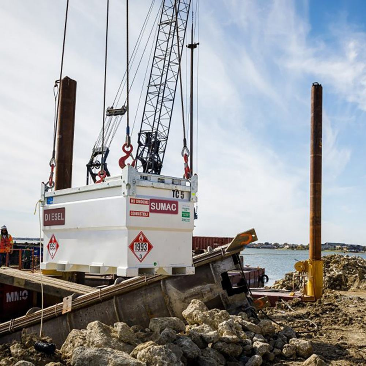 Crane lifting a SUMAC self-bunded diesel tank into position on a marine construction site